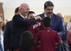 FIFA president Gianni Infantino, left, smiles after receiving the shirt of the Venezuelan soccer team with Venezuela President Nicolás Maduro, right, during his visit at Miraflores Presidential Palace in in Caracas, Venezuela , Friday , Oct 15, 2021. (AP Photo/Ariana Cubillos)