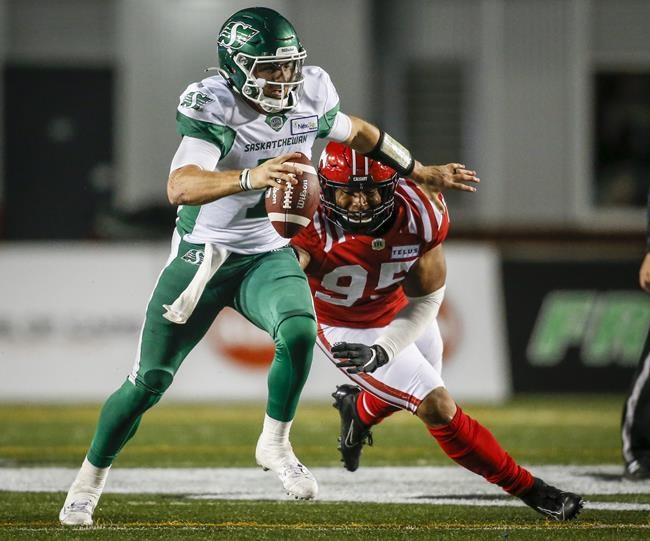 Saskatchewan Roughriders quarterback Cody Fajardo, left, is sacked by Calgary Stampeders' Stefen Banks during first half CFL football action in Calgary, Saturday, Oct. 23, 2021.THE CANADIAN PRESS/Jeff McIntosh