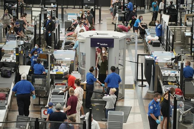 FILE - Travelers wear face coverings in the line for the south security checkpoint in the main terminal of Denver International Airport on Aug. 24, 2021, in Denver. The Biden administration is detailing its new international COVID-19 air travel polices, which will include exemptions for kids and new federal contact tracing requirements. (AP Photo/David Zalubowski)