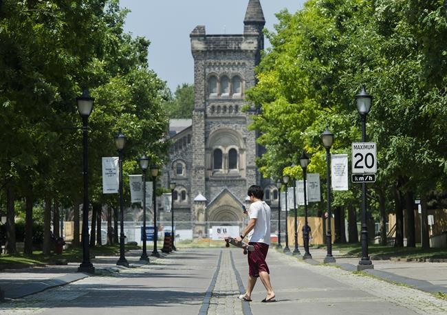 A person walks past the University of Toronto campus during the COVID-19 pandemic in Toronto, Wednesday, June 10, 2020. The University of Toronto says it will sell off all fossil fuel investments in its $4 billion endowment by the end of 2030 and target a net-zero portfolio by 2050 to help fight climate change. THE CANADIAN PRESS/Nathan Denette