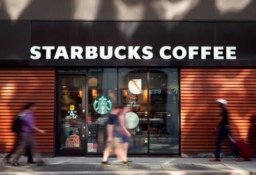 Pedestrians walk past a downtown Toronto Starbucks Coffee location Thursday, May 31, 2018.&nbsp;Starbucks Canada is raising its hourly starting wage to one dollar above provincial minimums in January, while baristas who have been with the company a year will receive a six to 10 per cent pay hike. THE CANADIAN PRESS/Graeme Roy