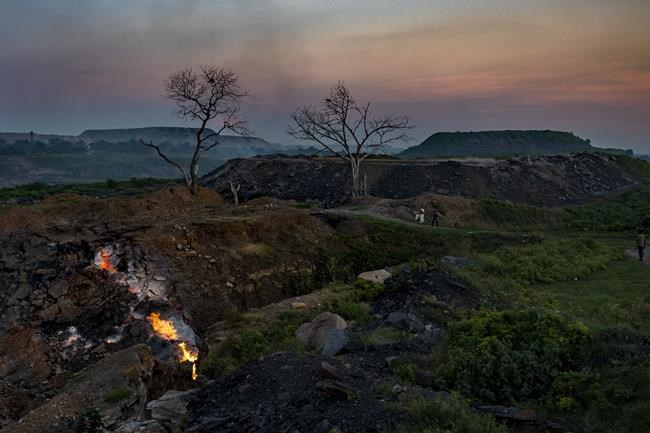 FILE - Flames rise out of fissures in the ground above coal mines in the village of Liloripathra near Dhanbad, an eastern Indian city in Jharkhand state, Friday, Sept. 24, 2021. (AP Photo/Altaf Qadri, File)