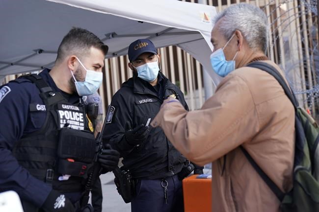 United States customs officers speak with a man at the San Ysidro Port of Entry, Monday, Nov. 8, 2021, in Tijuana, Mexico. The U.S. fully reopened its borders with Mexico and Canada on Monday and lifted restrictions on travel that covered most of Europe, setting the stage for emotional reunions nearly two years in the making and providing a boost for the travel industry decimated by the pandemic. (AP Photo/Gregory Bull)