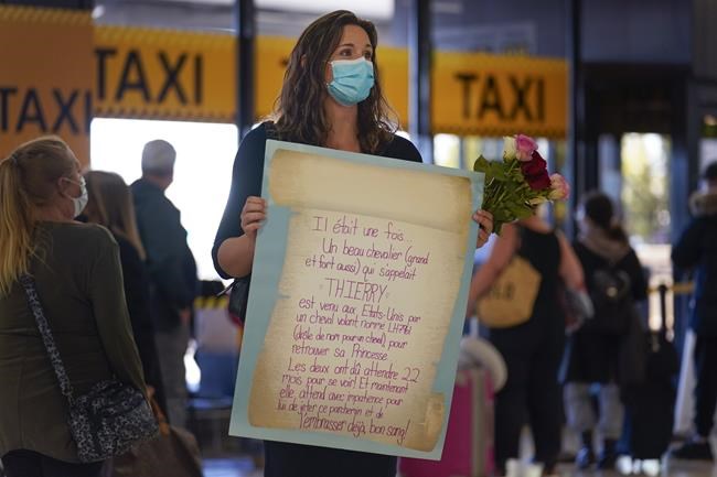 MaKensi Kastl waits with flowers and sign for her boyfriend, who is arriving from France, at Newark Liberty International Airport in Newark, N.J., Monday, Nov. 8, 2021. The couple has not seen one another in person for over a year due to pandemic travel restrictions. The U.S. lifted restrictions Monday on travel from a long list of countries including Mexico, Canada and most of Europe, setting the stage for emotional reunions nearly two years in the making and providing a boost for the airline and tourism industries decimated by the pandemic. (AP Photo/Seth Wenig)
