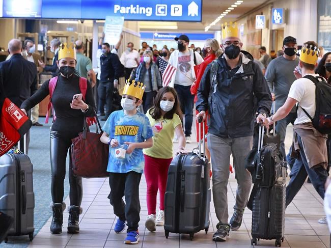 A family arriving on a Virgin Atlantic flight from Manchester, England to Orlando International Airport heads to baggage claim, Monday, Nov. 8, 2021. The nonstop flight was the first for international passengers to Orlando after more than 19 months without traditional transatlantic airline service. Gold paper crowns were distributed to the arriving passengers as a welcome gesture from the Greater Orlando Aviation Authority. (Joe Burbank/Orlando Sentinel via AP)