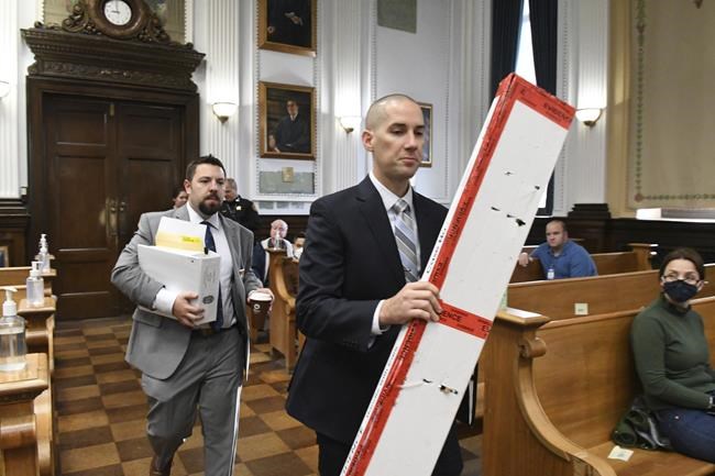 Kenosha Police Detectives Ben Antaramian, left, and Martin Howard, carry evidence including Kyle Rittenhouse's rifle and bullets into court during the trial at the Kenosha County Courthouse in Kenosha, Wis., on Tuesday, Nov. 9, 2021. Rittenhouse is accused of killing two people and wounding a third during a protest over police brutality in Kenosha, last year. (Mark Hertzberg /Pool Photo via AP)