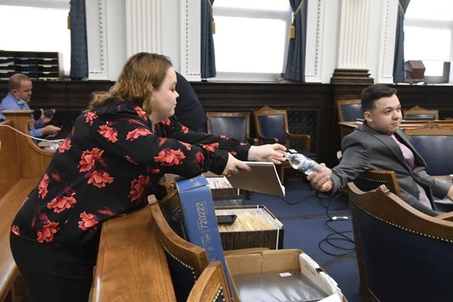 Kyle Rittenhouse hands his mother Wendy Rittenhouse a bottle of water before the start of his trial at the Kenosha County Courthouse in Kenosha, Wis., on Tuesday, Nov. 9, 2021. Rittenhouse is accused of killing two people and wounding a third during a protest over police brutality in Kenosha, last year. (Mark Hertzberg /Pool Photo via AP)