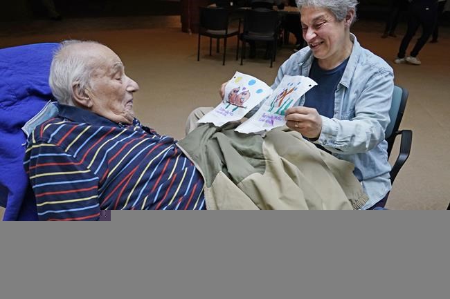 FILE - Melvin Goldstein, 90, glances at pictures of birds, left, and a fish, his 13-year-old granddaughter drew for him as a gift as his daughter Barbara Goldstein shares them with his during a family visit inside the Hebrew Home at Riverdale, March 28, 2021, in New York. The government on Friday, Nov. 12, directed nursing homes to open their doors wide to visitors, easing many remaining pandemic restrictions while urging residents, families and facility staff to keep their guard up against outbreaks. (AP Photo/Kathy Willens, File)