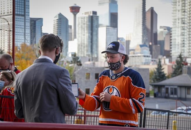 An Edmonton Oiler fan has their COVID-19 vaccination proof checked before entering the Saddledome for pre-season NHL hockey action in Calgary, Alta., Sunday, Sept. 26, 2021. Starting today in Alberta, you're going to need more than a sheet of paper you got from a COVID-19 vaccine clinic in order to sit down at a restaurant, work out at a gym or gain entry to many venues like indoor arenas or movie theatres. THE CANADIAN PRESS/Jeff McIntosh