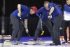 From left, Team Shuster's Chris Plys sweeps to curl the rock alongside John Shuster and John Landsteiner while competing against Team Dropkin during the second night of finals at the U.S. Olympic Curling Team Trials at Baxter Arena in Omaha, Neb., Saturday, Nov. 20, 2021. (AP Photo/Rebecca S. Gratz)