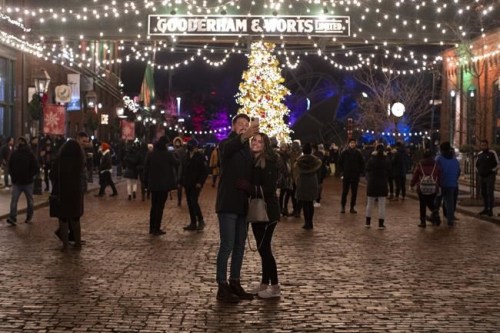 Visitors take photos in Toronto's Distillery District, on Saturday, December 19, 2020. Almost half of Canadians plan to abandon social distancing during holiday gatherings and hug, kiss and shake hands with friends and family, a poll shows. THE CANADIAN PRESS/Chris Young