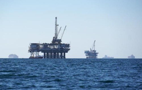 FILE - Cargo vessels are seen anchored offshore, sharing space with oil platforms, before heading into the Los Angeles-Long Beach port on Oct. 5, 2021. Oregonians are increasingly pushing for the state to divest from fossil fuel companies and other controversial investments, but the state treasury is resisting and putting the onus for any transformation on the Legislature. (AP Photo/Eugene Garcia, File)