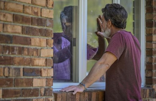 FILE - Jack Campise talks with his mother, Beverly Kearns, through her apartment window at the Kimberly Hall North nursing home, Thursday, May 14, 2020 in Windsor, Conn. Connecticut essential state employees, such as nurses, long-term care workers, prison staff and first responders who worked long hours during the COVID-19 pandemic, are still waiting for 