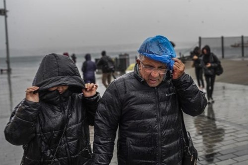 People run under a heavy rain during a stormy day in Istanbul, Turkey, Monday, Nov. 29, 2021. A powerful storm pounded Istanbul and other parts of Turkey on Monday, killing at least four people and causing havoc in the city of 15 million people, reports said. (AP Photo)