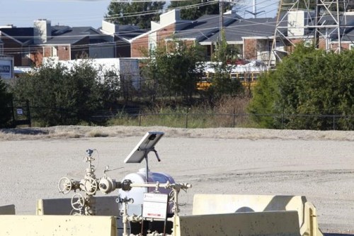 A natural gas well is juxtaposed with apartment buildings a few hundred feet away in Arlington, Texas, on Monday, Oct. 25, 2021. The site, known as 