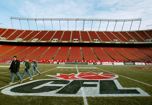 Workers Bruce Simpson, left to right, Jamie Cartwell and Jason Tichon walk across the field next to the CFL logo at Commonwealth Stadium in Edmonton, Thursday, Nov. 21, 2002. A new national survey indicates many Canadians don't want the NFL here at the expense of the CFL but may also reinforce the biggest challenge facing the Canadian league. THE CANADIAN PRESS/Kevin Frayer