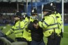 A supporter is detained by police officers during the English Premier League soccer match between Everton and Liverpool at Goodison Park in Liverpool, England, Wednesday, Dec. 1, 2021. Liverpool won 4-1. (AP Photo/Jon Super)