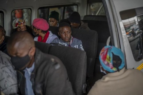 Passengers, some wearing masks, wait for their taxi to leave the Baragwanath taxi rank in Soweto, South Africa, Thursday Dec. 2, 2021. South Africa launched an accelerated vaccination campaign to combat a dramatic rise in confirmed cases of COVID-19 a week after the omicron variant was detected in the country. (AP Photo/Jerome Delay)