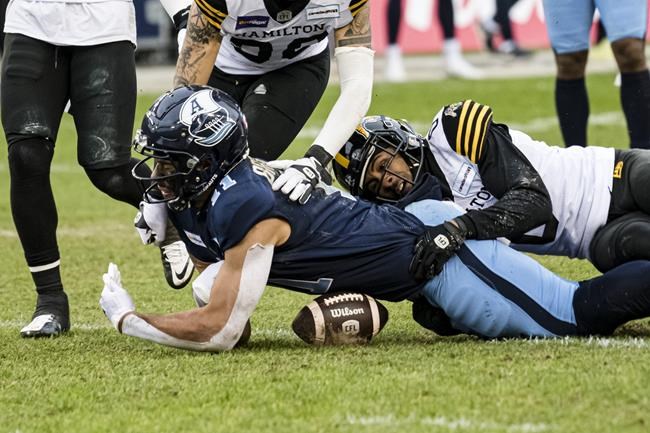 Toronto Argonauts wide receiver Juwan Brescacin (11) is tackled by Hamilton Tiger-Cats defensive back Ciante Evans (0) defensive back Stavros Katsantonis (30) during second half CFL Eastern Conference final action in Toronto, on Sunday, December 5, 2021. THE CANADIAN PRESS/Christopher Katsarov