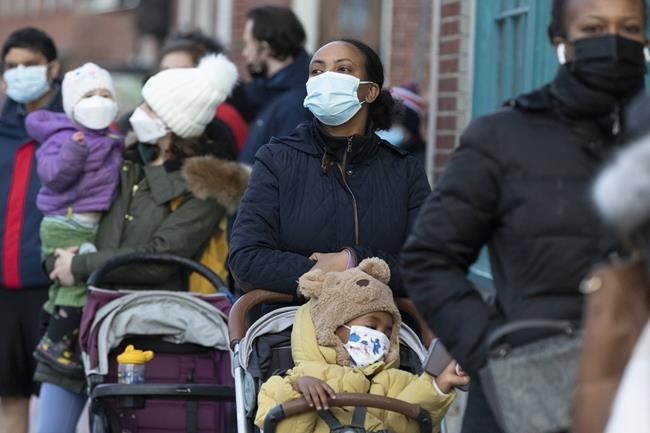 Makda Yesuf, center, and her son Jaden wait in line at a COVID-19 walk-in testing site, Sunday, Dec. 5, 2021, in Cambridge, Mass. (AP Photo/Michael Dwyer)