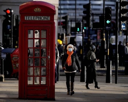 People wear face coverings as they walk through Westminster, in London, Thursday, Dec. 9, 2021. British Prime Minister Boris Johnson has announced tighter restrictions to stem the spread of the omicron variant. He is again urging people to work from home and mandating COVID-19 passes to get into nightclubs and large events. (AP Photo/Frank Augstein)