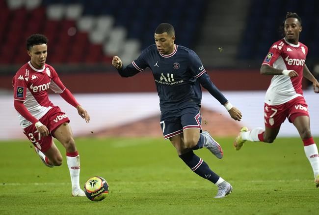 PSG's Kylian Mbappe, centre, challenges for the ball with Monaco's Sofiane Diop, left, during the French League One soccer match between Paris Saint-Germain and Monaco at the Parc des Princes stadium in Paris, France, Sunday, Dec. 12, 2021. (AP Photo/Christophe Ena)