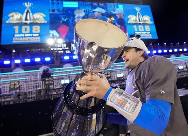 Winnipeg Blue Bombers quarterback Zach Collaros (8) hoists the Grey Cup as the Blue Bombers celebrate their win over the Hamilton Tiger-Cats in the 108th CFL Grey Cup in Hamilton, Ont., on Sunday, December 12, 2021. THE CANADIAN PRESS/Nathan Denette