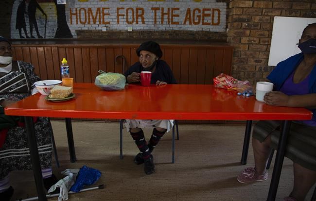 People living at the Soweto Home For The Aged practice social distancing during breakfast in Johannesburg, Tuesday, Dec. 14, 2021. An analysis of data from South Africa shows the omicron variant appears to cause less severe disease than previous versions of the coronavirus, and the Pfizer vaccine seems to offer less defense against infection from it but still good protection against hospitalization. (AP Photo/Denis Farrell)