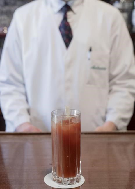 Bartender Antoine stands in front of a Bloody Mary cocktail at Harry's Bar in Paris, Friday, Dec. 10, 2021. Harry's Bar in Paris is celebrating the 100th birthday of the Bloody Mary, the vodka-tomato juice cocktail believed to have been invented in the iconic bar in 1921. The centenary events this week come as a welcome respite from winter gloom and spreading worries about the omicron virus variant. (AP Photo/Rafael Yaghobzadeh)