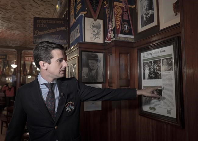 Franz-Arthur MacElhone, great-grandson of Harry MacElhone, points to an article at Harry's Bar in Paris, Friday, Dec. 10, 2021. Harry's Bar in Paris is celebrating the 100th birthday of the Bloody Mary, the vodka-tomato juice cocktail believed to have been invented in the iconic bar in 1921. The centenary events this week come as a welcome respite from winter gloom and spreading worries about the omicron virus variant. (AP Photo/Rafael Yaghobzadeh)