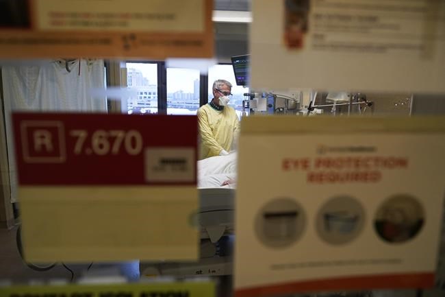 FILE - Steve Grove, a chaplain at Hennepin County Medical Center, prays in a COVID-19 patient's room, Dec. 10, 2021, in Minneapolis. The new omicron coronavirus mutant speeding around the world may bring another wave of chaos, threatening to further stretch hospital workers already struggling with a surge of delta cases and upend holiday plans for the second year in a row. (AP Photo/Charlie Neibergall, File)