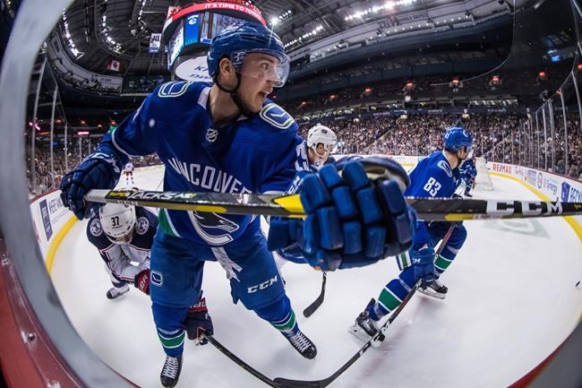 Vancouver Canucks' Ashton Sautner, front, watches the puck after Columbus Blue Jackets' Markus Hannikainen, back left, of Finland, dug it free and shot it around the boards during the third period of an NHL hockey game in Vancouver, B.C., Sunday, March 24, 2019. THE CANADIAN PRESS/Darryl Dyck