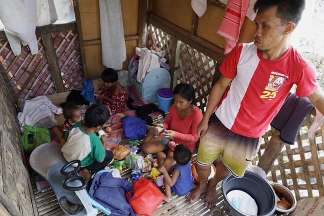 Alona Nacua, right seated, eats with her family as they stay at the house of their neighbor after their home got damaged due to Typhoon Rai in Cebu city, central Philippines on Christmas Day, Saturday, Dec. 25, 2021. Nacua said she and her husband managed to receive rice and four small cans of sardines and corned beef to be able to feed their family Saturday.