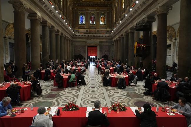 People sit at a Christmas day soup kitchen for fragile people, the poor, the homeless, and asylum seekers, set by the Sant'Egidio Community, at the Santa Maria in Trastevere Basilica in Rome, Saturday, Dec. 25, 2021. (AP Photo/Gregorio Borgia)