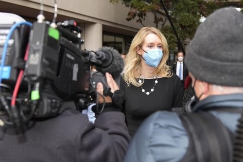 Former Theranos CEO Elizabeth Holmes, center, is followed by reporter as she leaves the U.S. Courthouse in San Jose, Calif., on Tuesday, Dec. 21, 2021. Holmes' trial revolves around allegations that she duped investors, business partners and patients about Theranos' technology. (AP Photo/Tony Avelar)