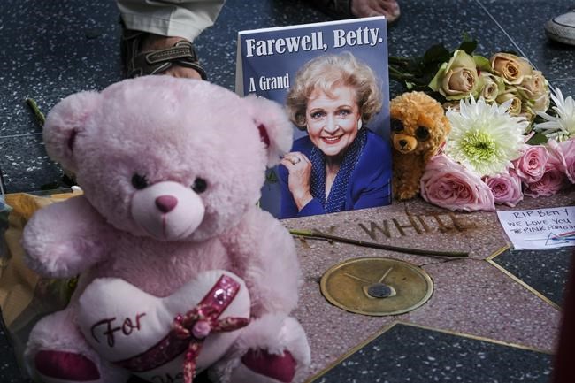 Flowers, stuff toys and cards are displayed at the Hollywood Walk of Fame star of the late actress Betty White, Friday, Dec. 31, 2021, in Los Angeles. White, whose saucy, up-for-anything charm made her a television mainstay for more than 60 years, whether as a man-crazy TV hostess on “The Mary Tyler Moore Show” or the loopy housemate on “The Golden Girls,” has died. She was 99.  (AP Photo/Ringo H.W. Chiu)