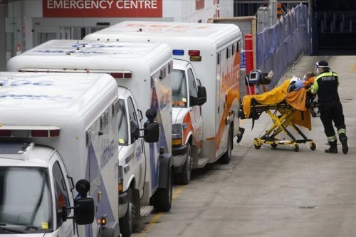 Paramedics wheel a patient past ambulances outside a hospital in Toronto on Wednesday, January 5, 2022.THE CANADIAN PRESS/Chris Young