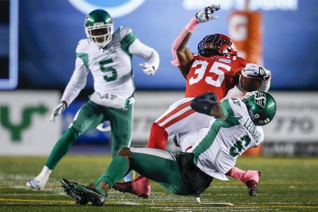 Saskatchewan Roughriders' A.C. Leonard, right, and Loucheiz Purifoy, left, bring down Calgary Stampeders' Ka'Deem Carey during first half CFL football action in Calgary, Saturday, Oct. 23, 2021.THE CANADIAN PRESS/Jeff McIntosh