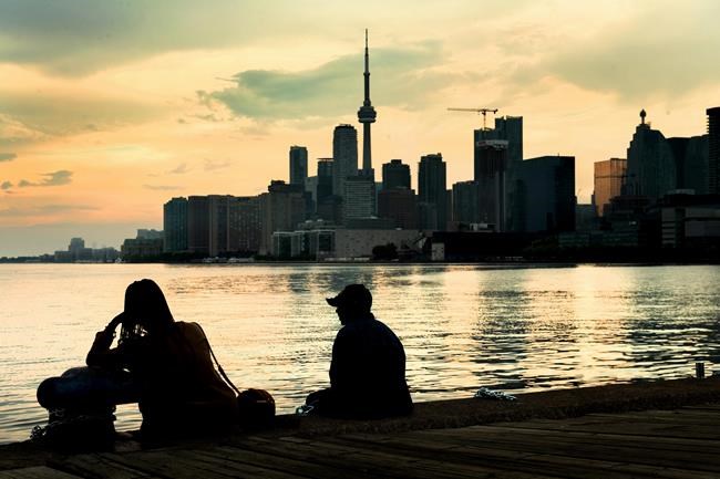 Two people sit and watch storm clouds passing by the skyline in Toronto on Tuesday, June 8, 2021. THE CANADIAN PRESS/Frank Gunn