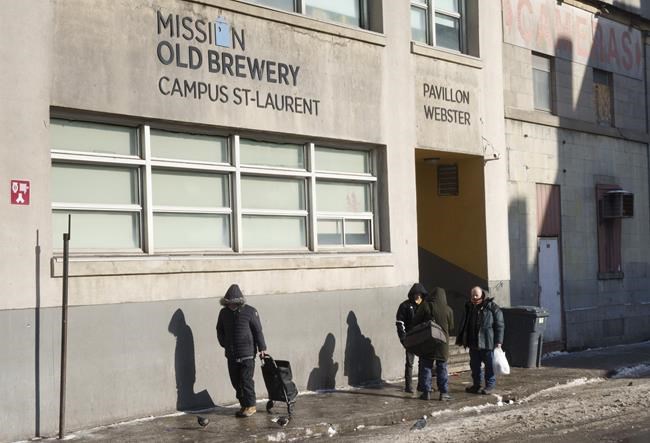 Homeless people stand outside the Old Brewery Mission in Montreal, on Monday, January 10, 2022. Homelessness sector staff continue to struggle to support those experiencing homelessness as the highly transmissible Omicron COVID-19 variant sweeps through communities. THE CANADIAN PRESS/Paul Chiasson
