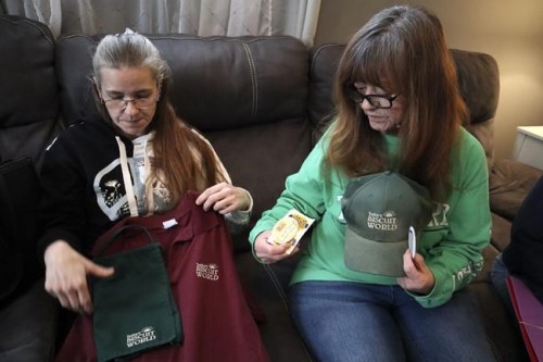 Former Tudor's Biscuit World employee Jennifer Patton, left, and current employee Cynthia Nicholson, right, show off their Tudor's Biscuit World uniforms and United Food & Commercial Workers Local 400 union stickers during an interview at Nicholson's Elkview, W.Va. home on Jan. 20, 2022. Patton said she was retaliated against and fired by management after she joined efforts to unionize the restaurant. Employees at the Elkview, W.Va., restaurant have already case ballots to decide whether or not they want to create a union. The votes will be read Tuesday. (AP Photo/Leah M. Willingham)