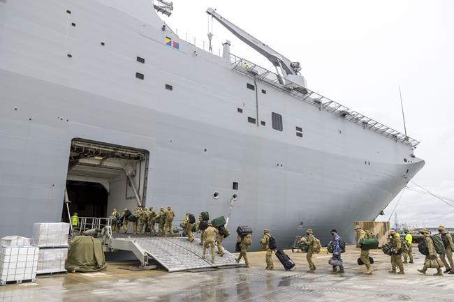 In this photo provided by the Australian Defense Force, soldiers load onto HMAS Adelaide at the Port of Brisbane before departing for Tonga Thursday, Jan. 20, 2022, after a volcano eruption. Nearly two dozen sailors aboard the Adelaide have tested positive for the coronavirus, officials said Tuesday, Jan 25, 2022, raising fears they could bring the disease to Tonga which has so far managed to avoid any outbreaks. (CPL Robert Whitmore/Australia Defense Force via AP)