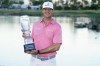Hudson Swafford holds the winner's trophy at the end of the American Express golf tournament on the Pete Dye Stadium Course at PGA West, Sunday, Jan. 23, 2022, in La Quinta, Calif. (AP Photo/Marcio Jose Sanchez)