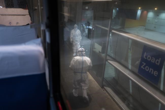 FILE - Two Olympic workers wearing protective gear work at a loading zone at the Beijing Capital International Airport ahead of the 2022 Winter Olympics in Beijing, Jan. 24, 2022. (AP Photo/Jae C. Hong, File)