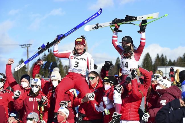 From right, top, winner Austria's Cornelia Huetter, and third placed Austria's Tamara Tippler celebrate with their team after an alpine ski, women's World Cup Super G race in Garmisch-Partenkirchen, Germany, Sunday, Jan. 30, 2022. (AP Photo/Pier Marco Tacca)