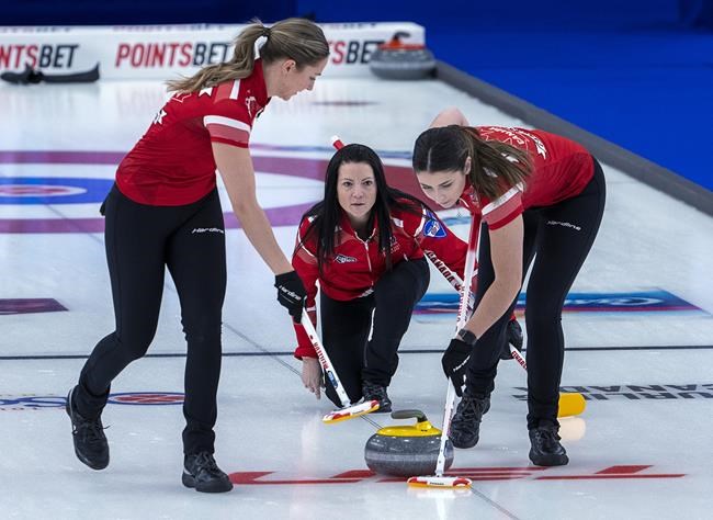 Team Canada skip Kerri Einarson releases a rock as lead Briane Meilleur, left, and second, Shannon Birchard sweep as they play Nova Scotia at the Scotties Tournament of Hearts at Fort William Gardens in Thunder Bay, Ont. on Sunday, Jan. 30, 2022. THE CANADIAN PRESS/Andrew Vaughan