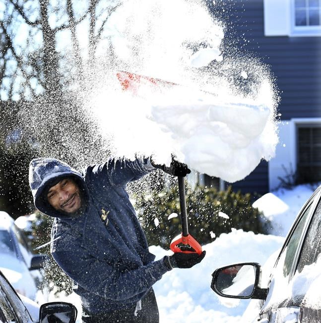 Lamont Bryant, a former NFL player with the Carolina Panthers and the Tennessee Titans, heaves snow from around his car on Mechanic Street in Attleboro, Mass., on Sunday, Jan. 30, 2022. Bryant, originally from Miami recently moved to Attleboro and said that this is his very first introduction to snow. Gusty winds and falling temperatures plunged the East Coast into a deep freeze as people dig out from a powerful nor'easter that dumped mounds of snow, flooded coastlines and knocked power out. (Mark Stockwell/The Sun Chronicle via AP)