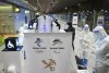Staff dressed in hazmat suits and safety gear direct people as they make their way through the first steps of customs, COVID-19 testing and accreditations upon arriving at the airport for the Beijing Winter Olympics in Beijing, China, on Monday Jan. 31, 2022. THE CANADIAN PRESS/Sean Kilpatrick
