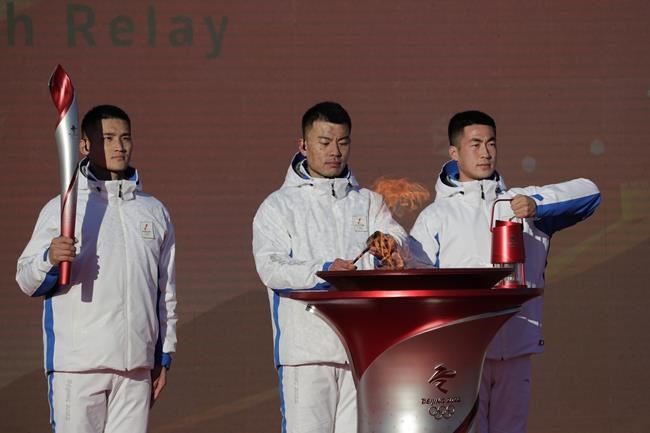 Workers prepare the flame for the start of the torch relay for the 2022 Winter Olympics at the Olympic Forest Park in Beijing on Wednesday, Feb. 2, 2022. (AP Photo/Sam McNeil)