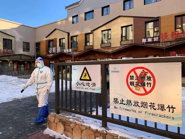 A worker walks in front of stores and restaurants in the hotel compound in Zhangjiakou, China at the 2022 Winter Olympics on Wednesday, February 2, 2022. Lunar New Year celebrations were muted in the Olympics host cities on Tuesday night.Signs in hotel compounds for athletes, media, and visiting officials in Zhangjiakou, China, forbade the use of fireworks or firecrackers. THE CANADIAN PRESS/John Chidley-Hill